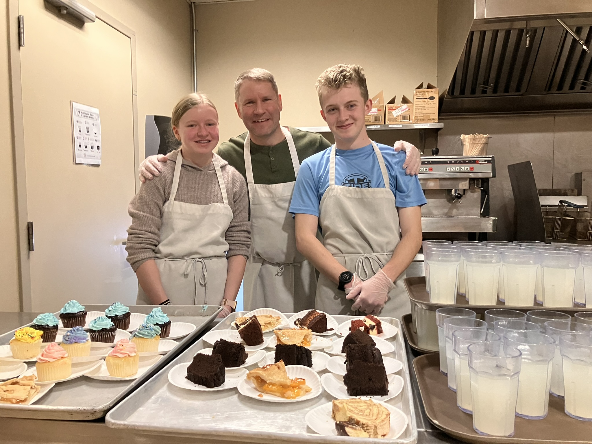 Three volunteers in the kitchen smiling