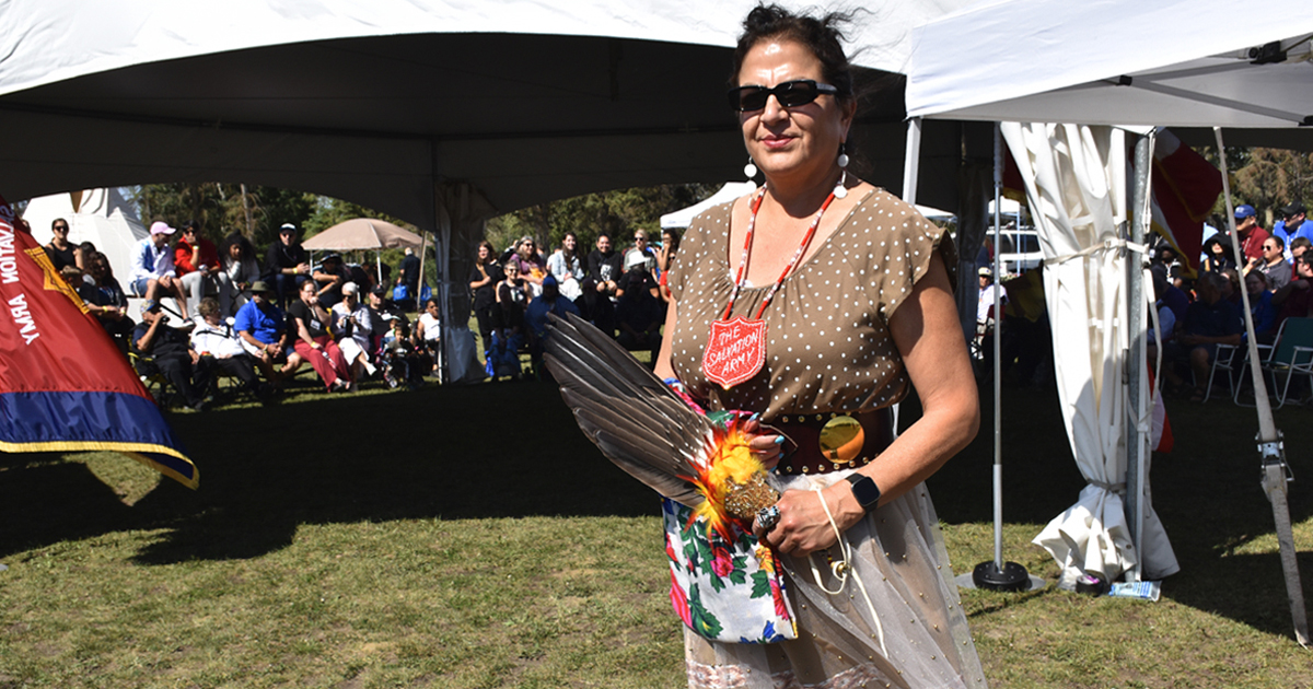 An Indigenous woman standing outside by a tent