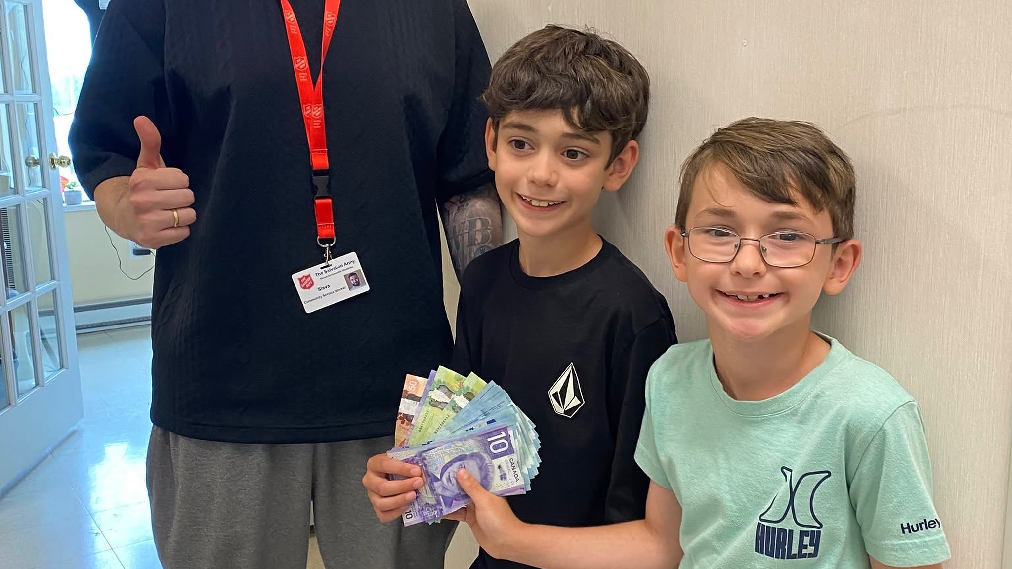 Chase and Rylan hand cash to Salvation Army worker
