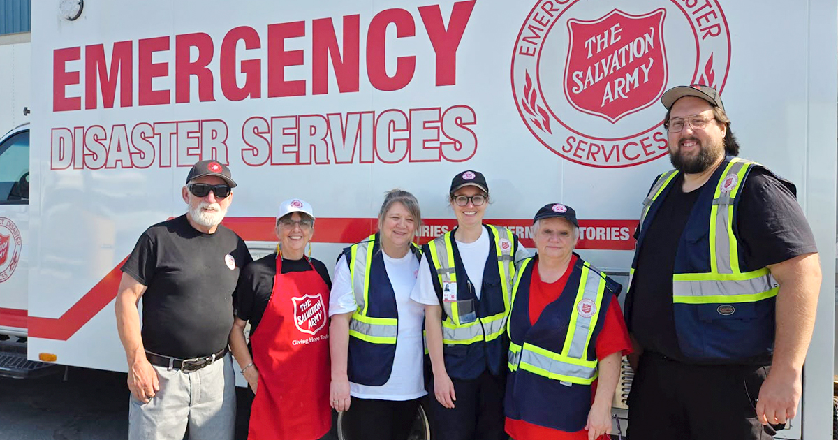 A group of six people standing in front of an emergency disaster services truck