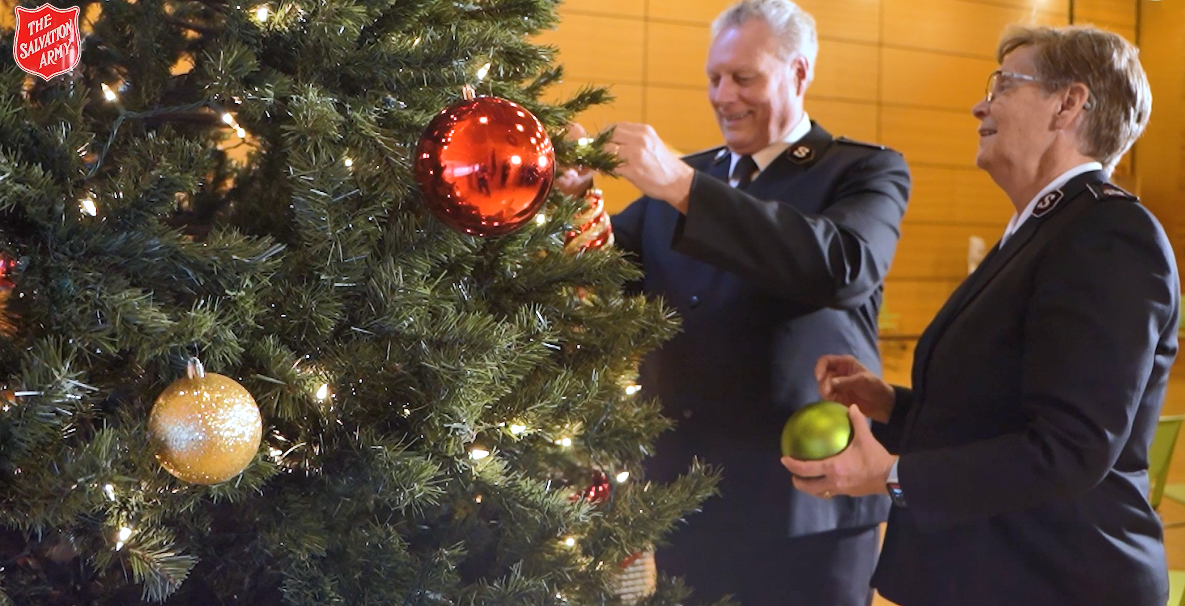 A man and a woman decorating a Christmas tree